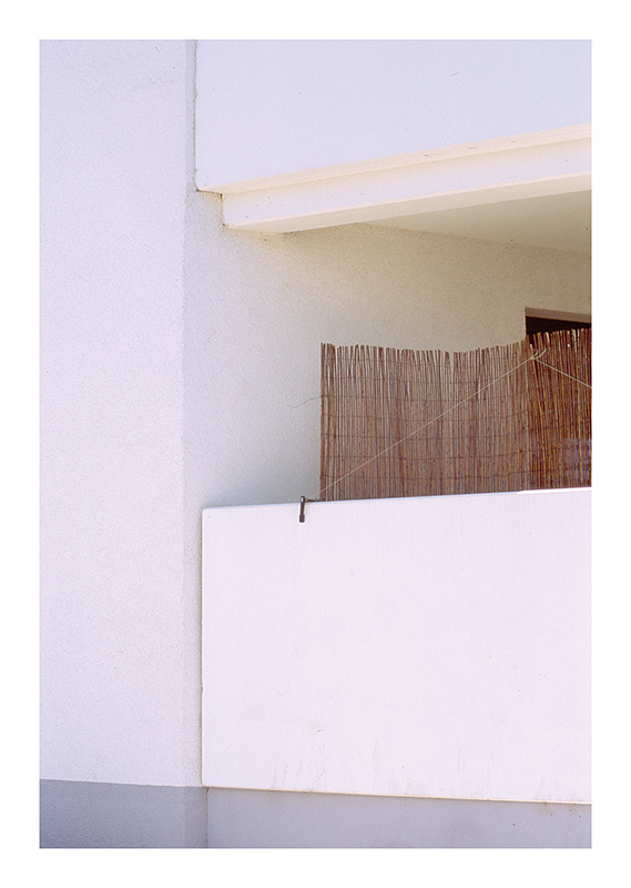 Weißer Balkon mit Bast-Sichtschutz