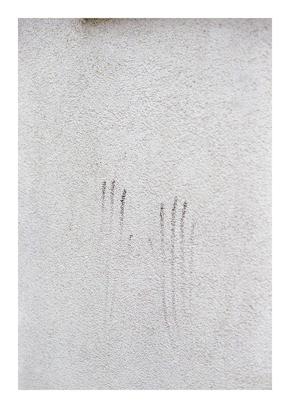 Schwarze Spuren zweier Hände an Hauswand, oben Fenstersims